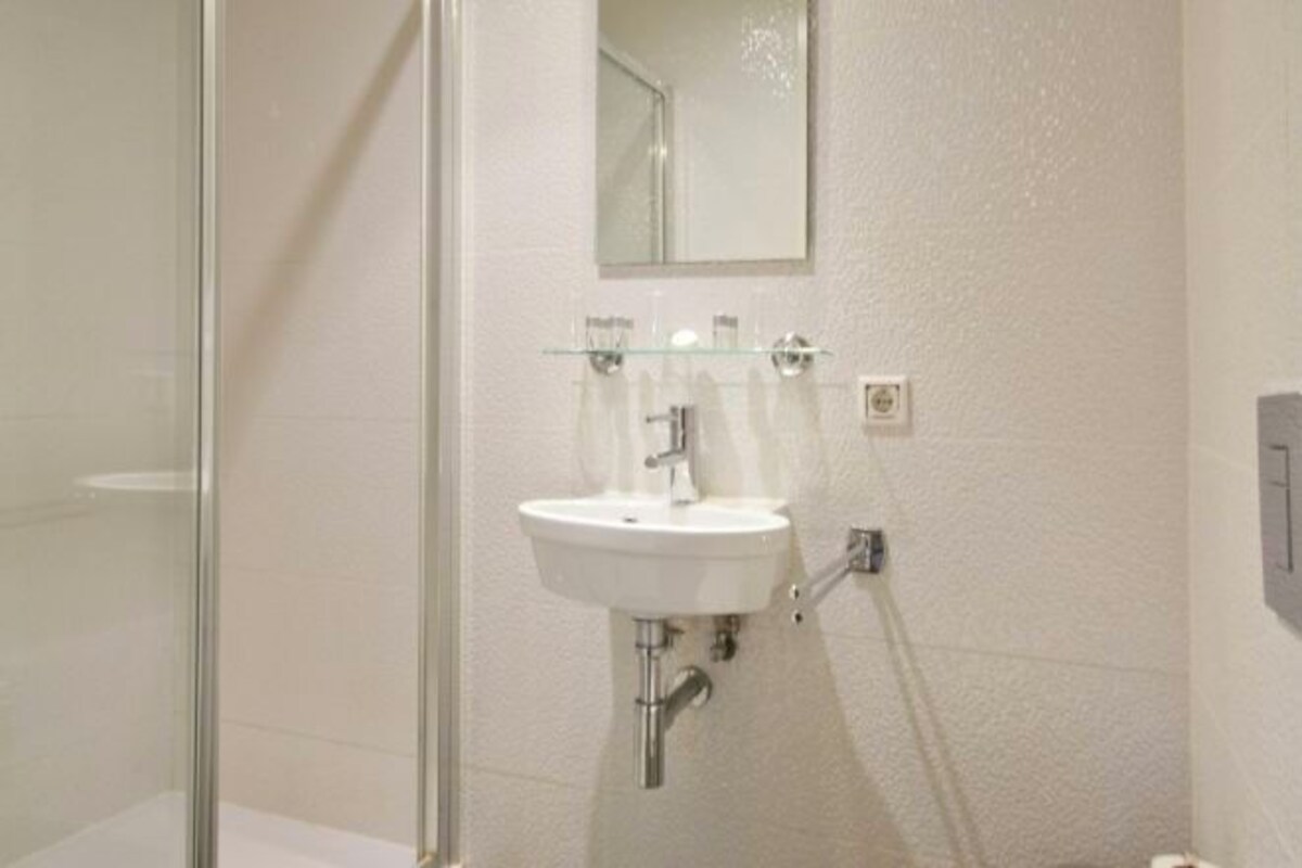 A bathroom with a white sink, a glass shower enclosure, and a mirror above the sink.