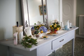 A white dresser with a mirror, a vase of flowers, and various food items. - Palazzo Bregante (Monopoli)