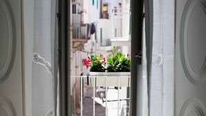 A narrow corridor with a balcony featuring potted plants and flowers. - Palazzo Bregante (Monopoli)