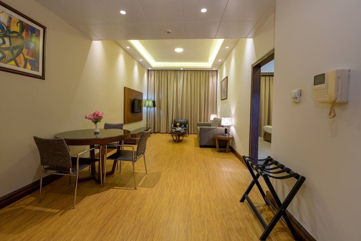 Ein Hotelzimmer mit Essbereich, Fernseher, Sofa, Lampe und Telefon.