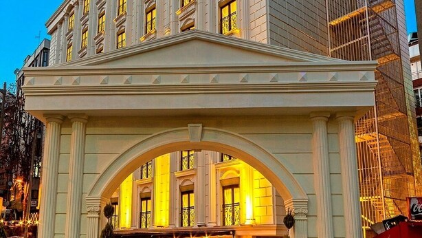 Una entrada de hotel con un arco clásico, múltiples ventanas y un cartel de Coca-Cola.
