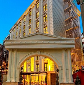 A hotel entrance with a classical archway, multiple windows, and a Coca-Cola sign. - Lausos Palace Hotel (Istanbul)