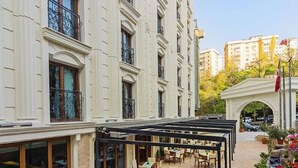 Un edificio con una zona de estar exterior techada, ventanas amplias y un arco decorativo.