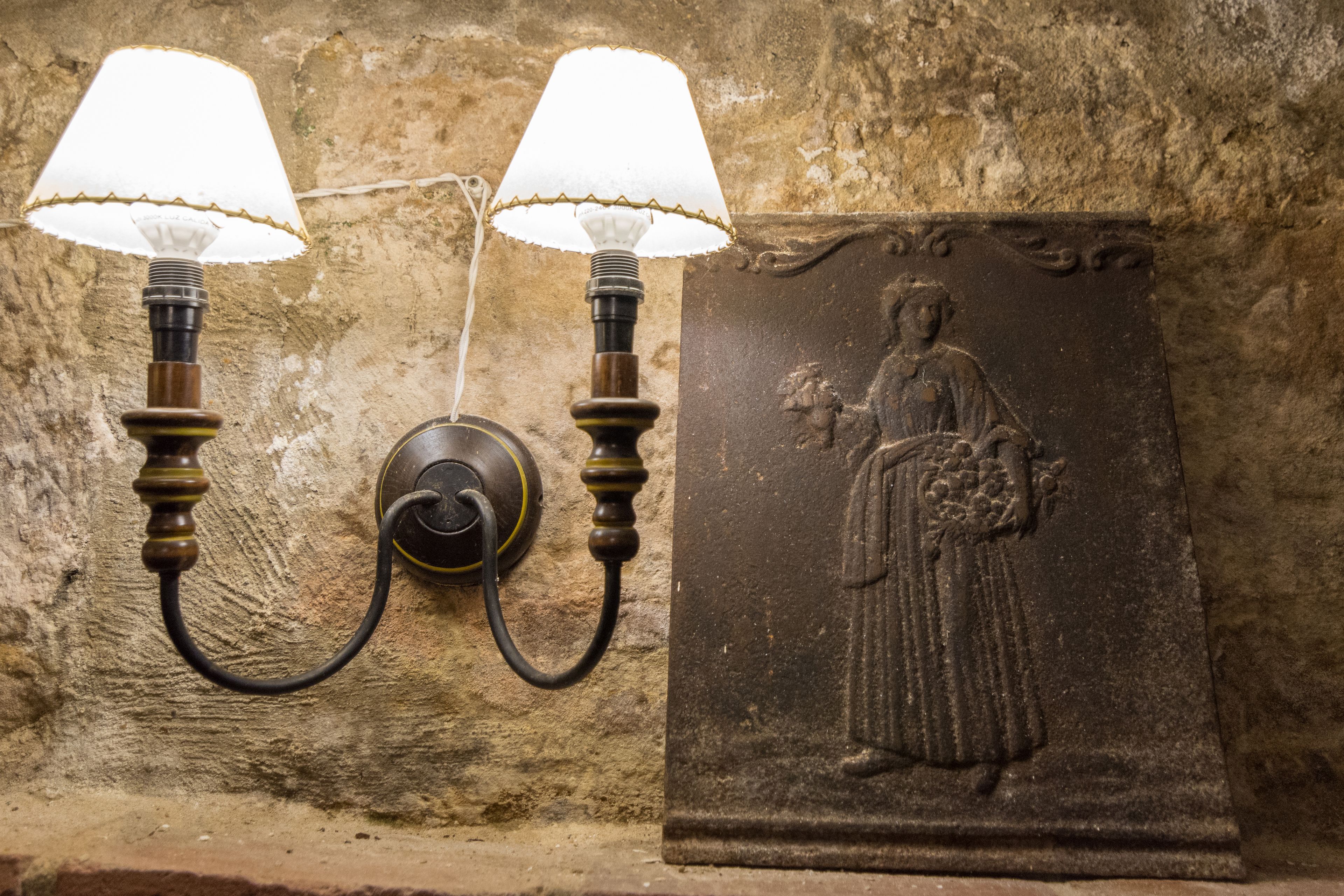 A wall-mounted light fixture with two lamps and a relief sculpture.
