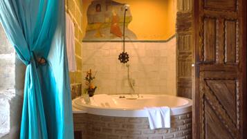 A bathroom with a bathtub, a wooden bench, a curtain, and a tiled floor.