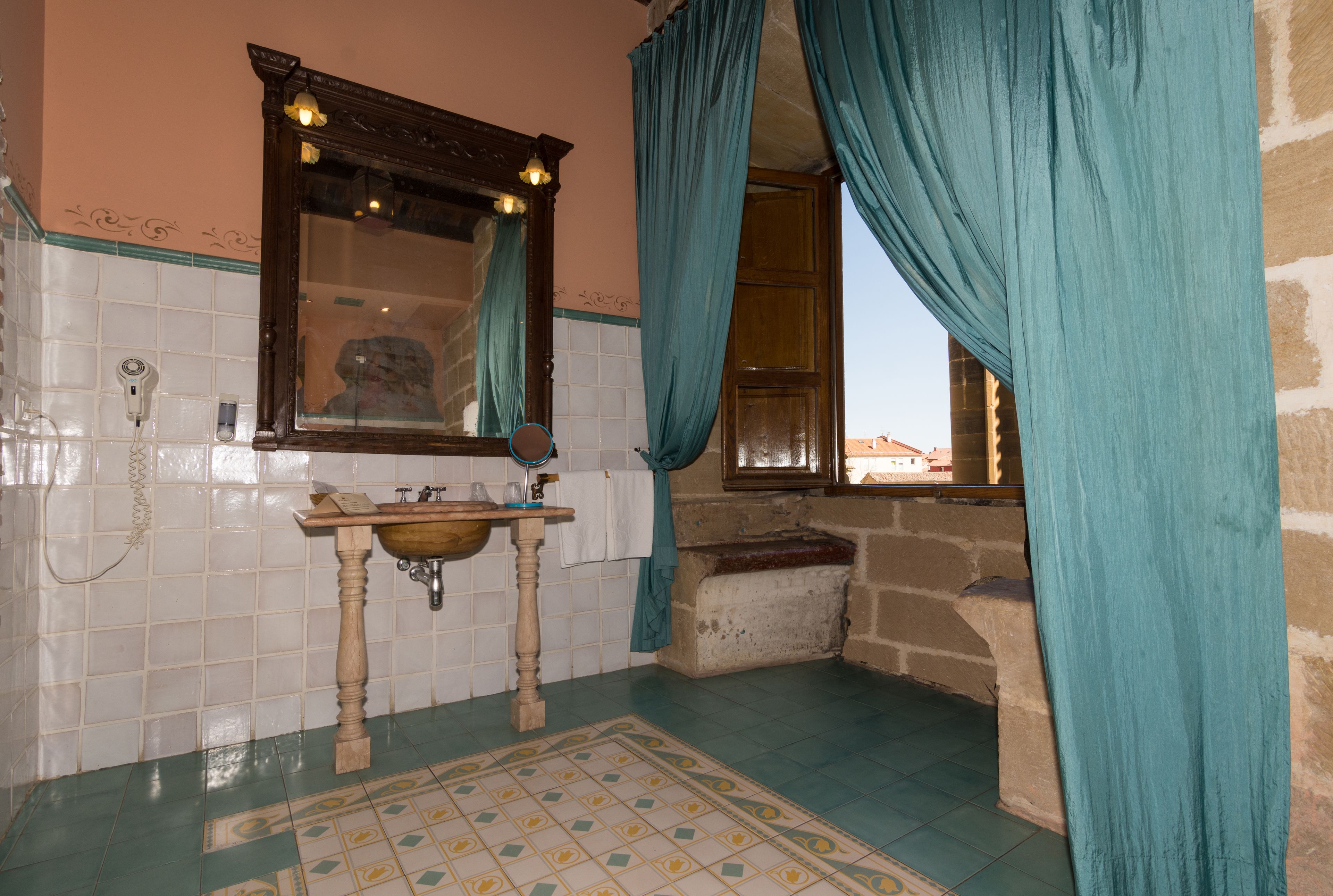Une salle de bain avec un lavabo en bois, un miroir et une fenêtre avec des rideaux.
