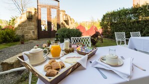 An outdoor breakfast setup with a tray of croissants, juice, and a teapot. - Hospedería Señorío de Casalarreina (Casalarreina)