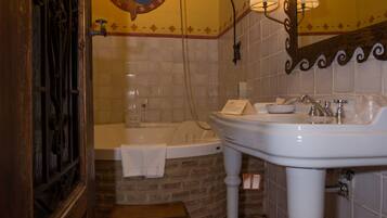 A bathroom with a white sink, a mirror, a bathtub, and a decorative tile floor.