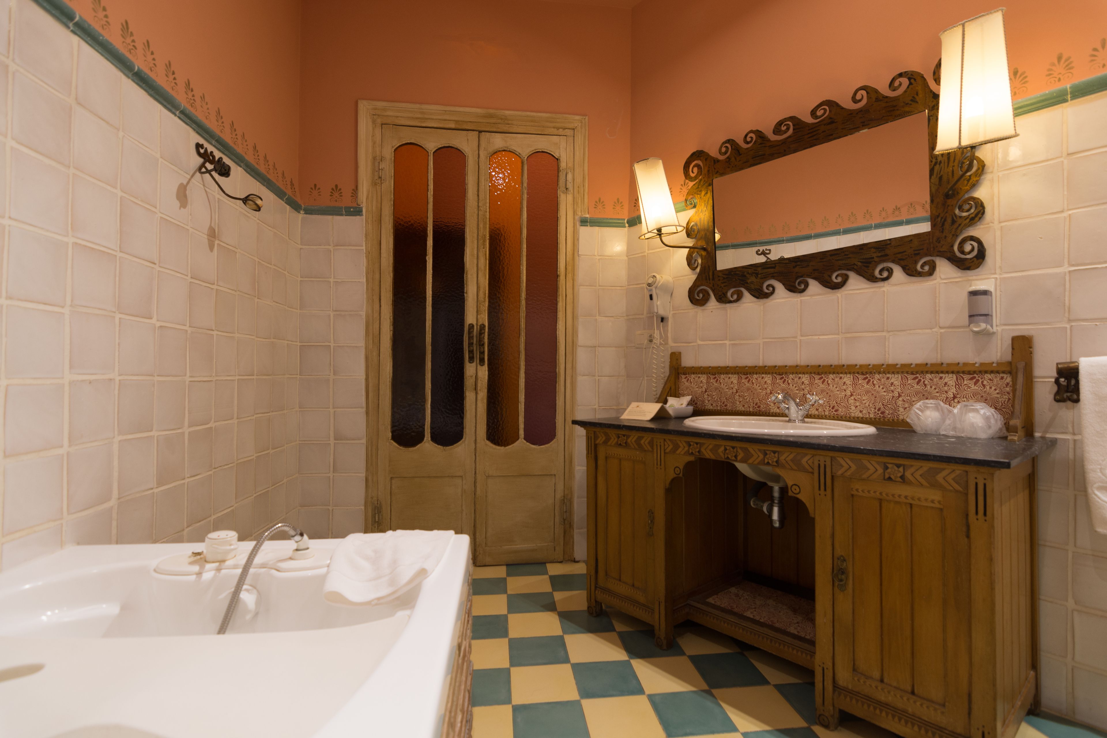 A bathroom with a checkered floor, a wooden vanity with a sink, a mirror, and a bathtub.
