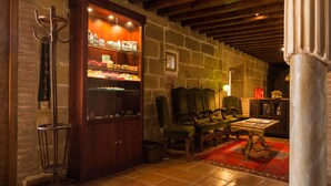 A cozy room with a wooden cabinet displaying various items, a green armchair, a wooden table, and a patterned rug. - Hospedería Señorío de Casalarreina (Casalarreina)