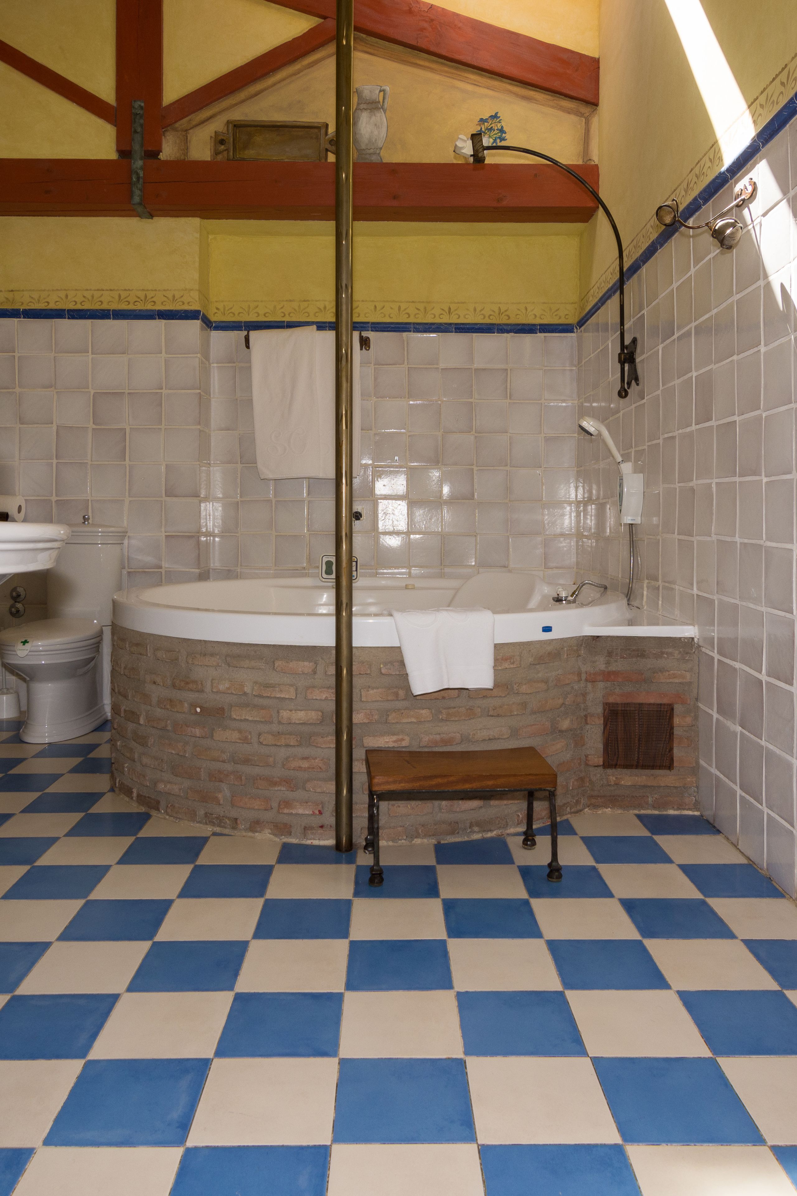 Un baño con piso a cuadros, una bañera, un inodoro y un lavamanos.