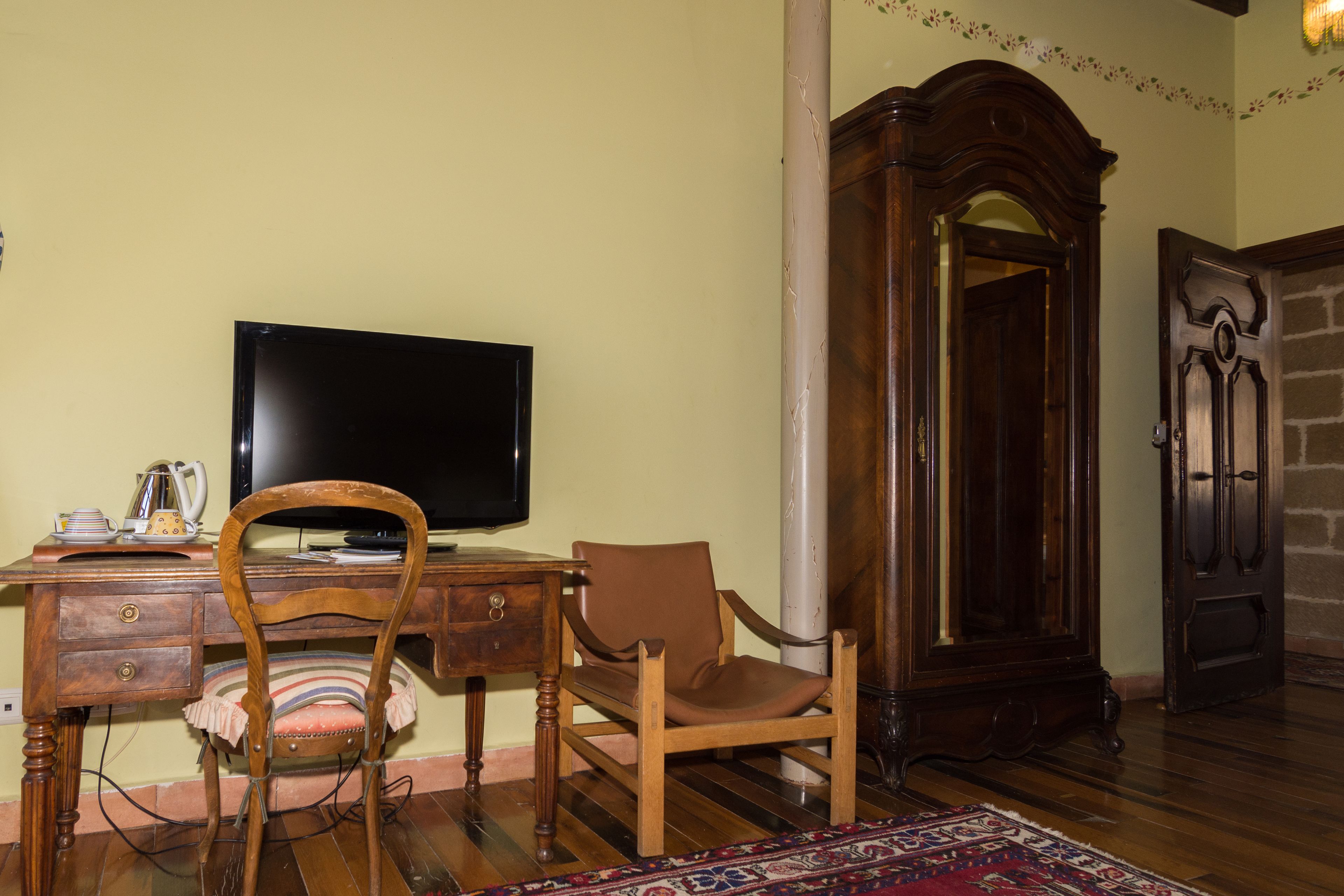 Une pièce comprenant un bureau en bois, une télévision, une chaise, un meuble et un tapis à motifs.