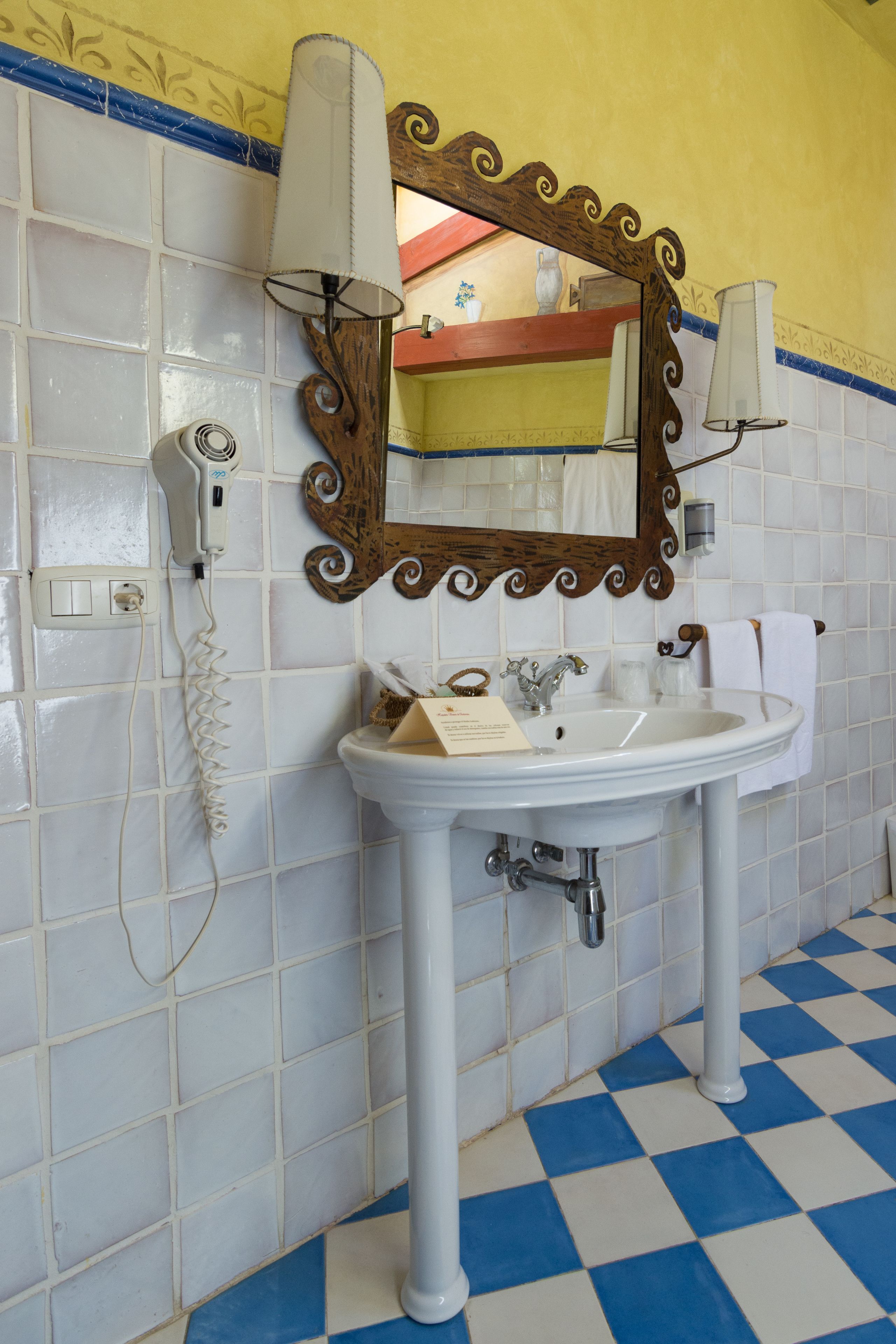 Un baño con lavamanos blanco, un espejo con marco de madera, un secador de pelo y un teléfono.