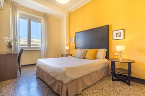 Ein Hotelzimmer mit einem Bett, zwei Nachttischen, einem Schreibtisch und einem Sessel.