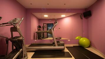 A home gym with a treadmill, elliptical, and exercise balls.