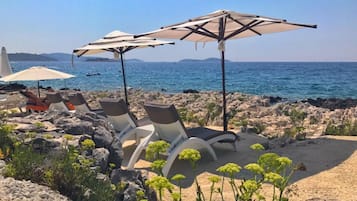 PĂ„ stranden, vit sandstrand, solstolar och parasoller