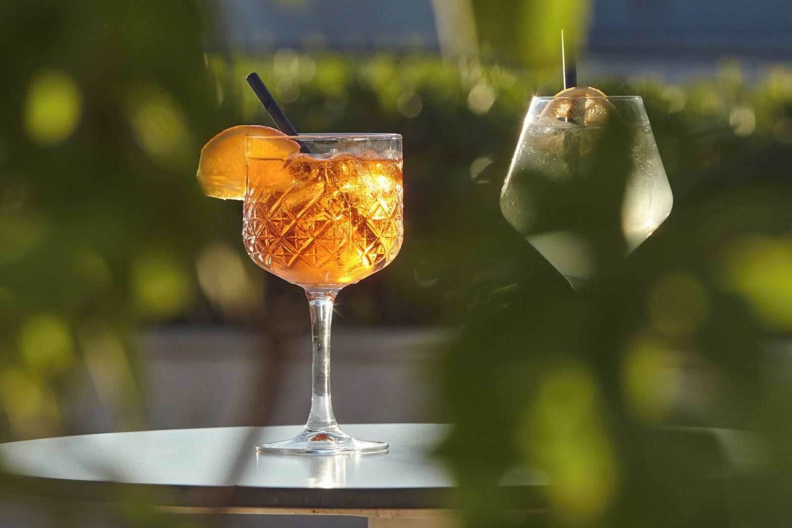 Ein Glas Eisgetränk mit einer Zitronenscheibe auf einem Tisch im Freien.