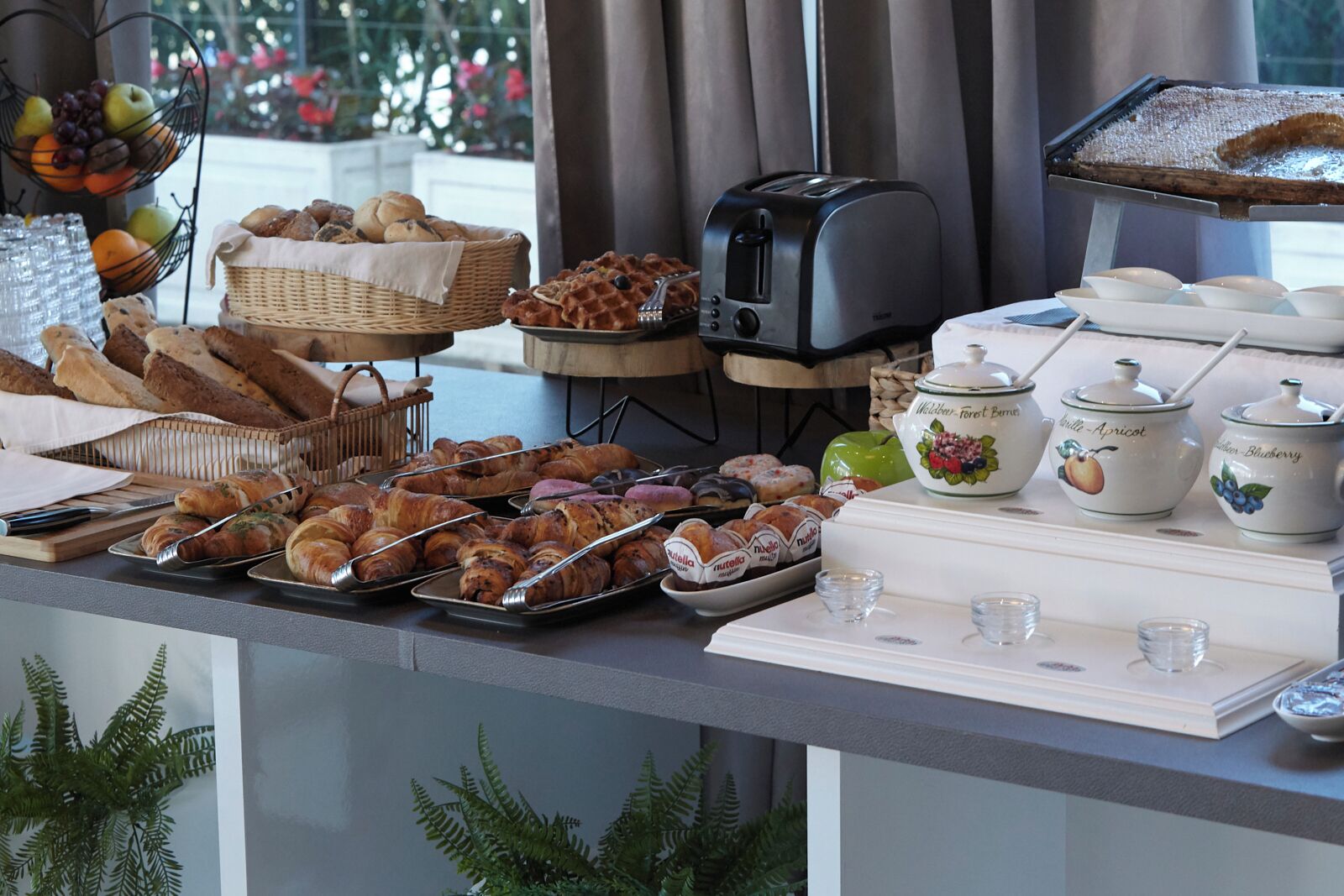 A breakfast buffet with various pastries, bread, and condiments.