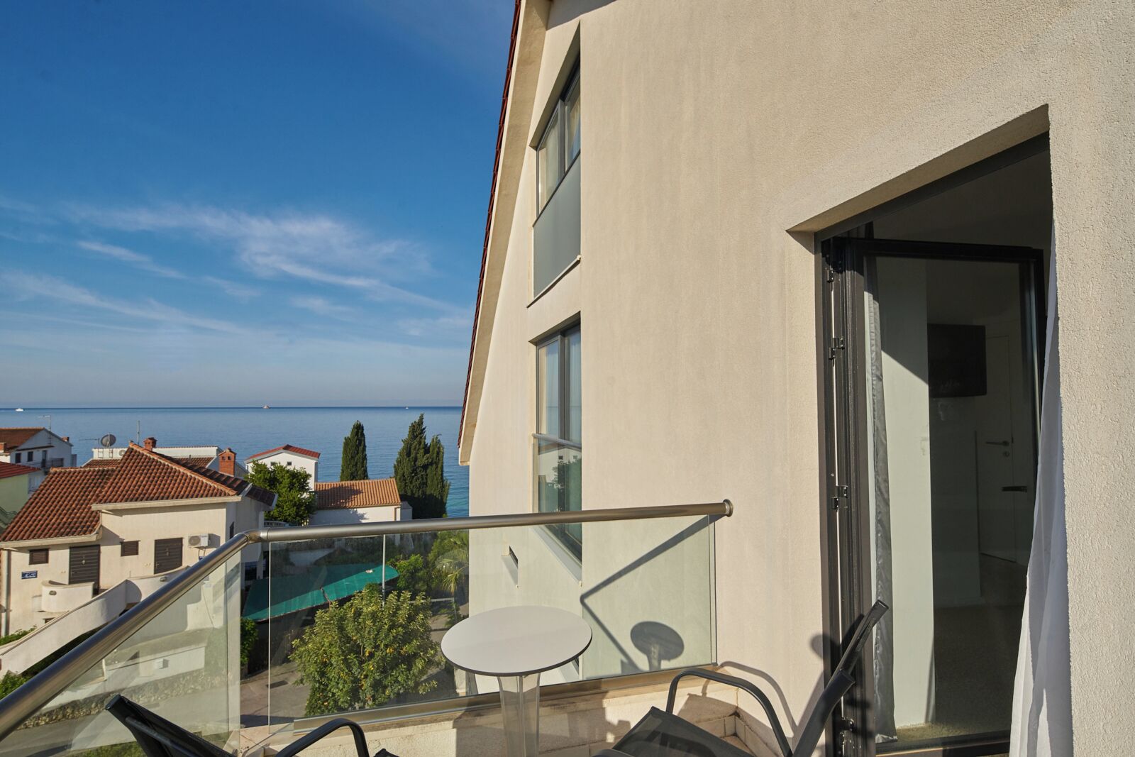 A balcony with a glass railing overlooking a sea view.