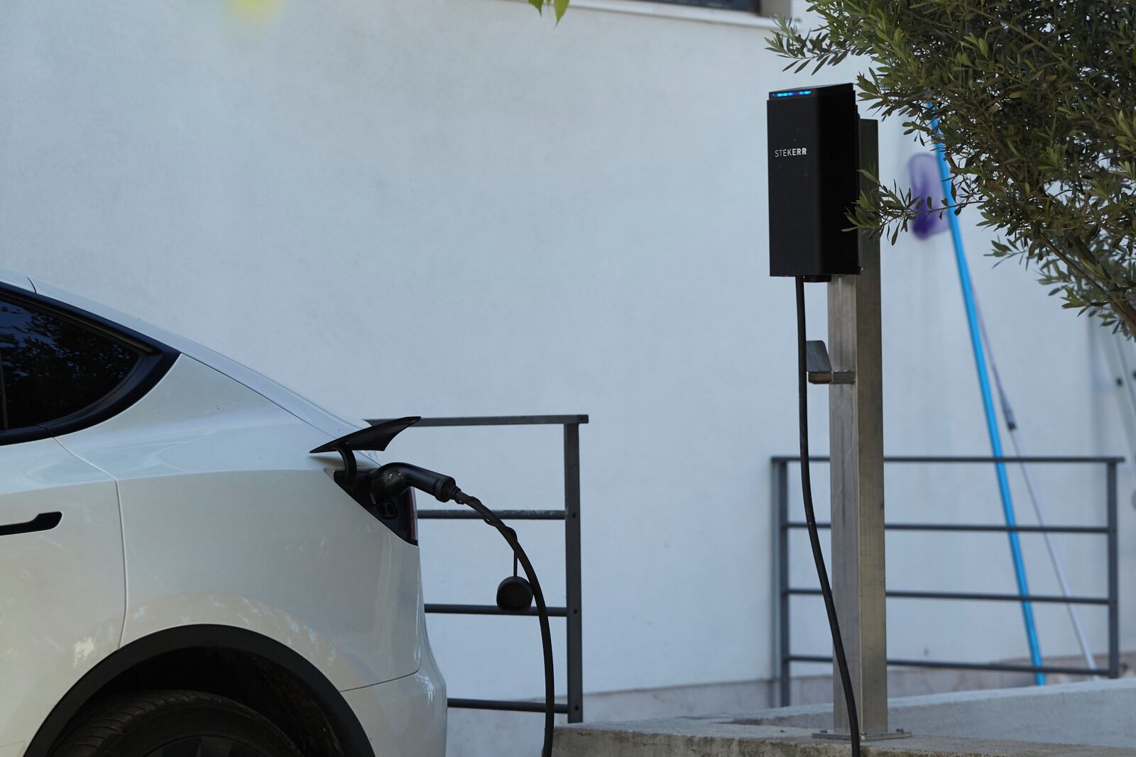 A white car connected to a charging station.