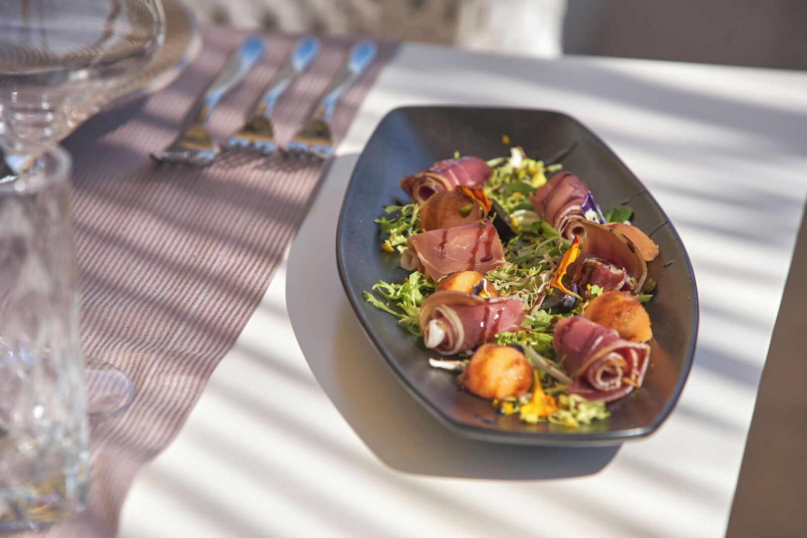 Een bord eten met gehakt vlees en groenten op een tafel met een geribbelde servet en bestek.