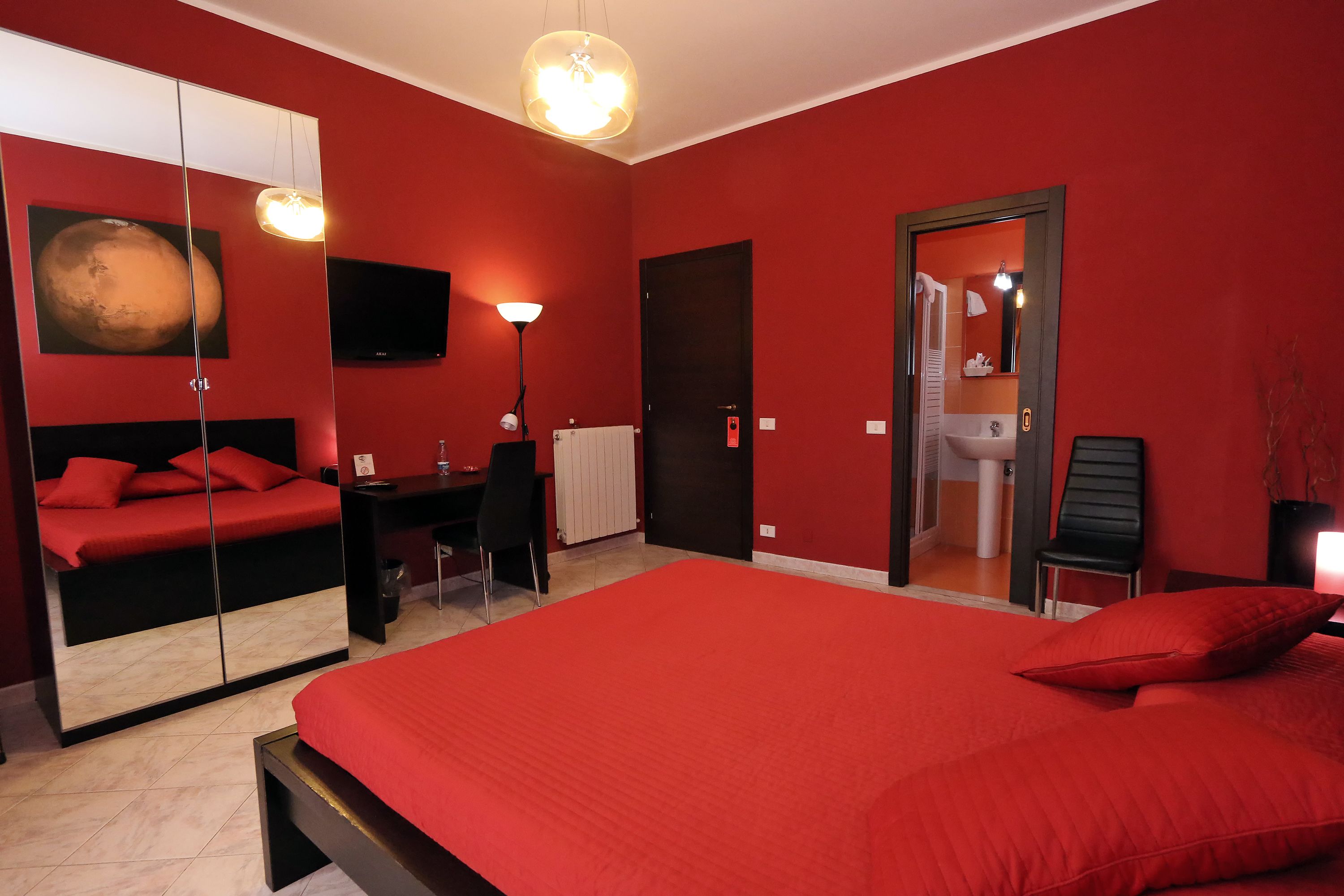 Une chambre à coucher avec un grand lit, un bureau, une chaise, un miroir et un téléviseur.