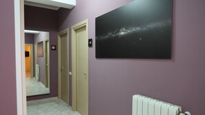 Um corredor com parede espelhada, pintura da galáxia e radiador.