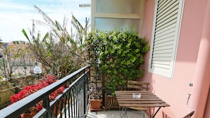 Uma varanda com mesa e cadeiras de madeira, plantas em vasos e vista da região.