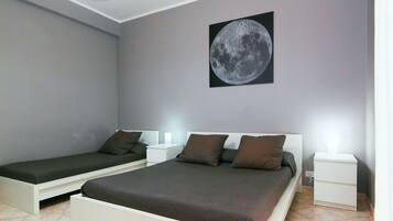 A bedroom with two single beds, a nightstand with a lamp, and a wall-mounted picture of the moon.