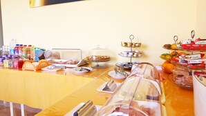 Uma mesa de buffet com diversos alimentos e bebidas, incluindo pizza, frutas e lanches embalados.