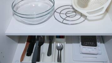 A kitchen counter with a glass bowl, colander, and utensil holder.