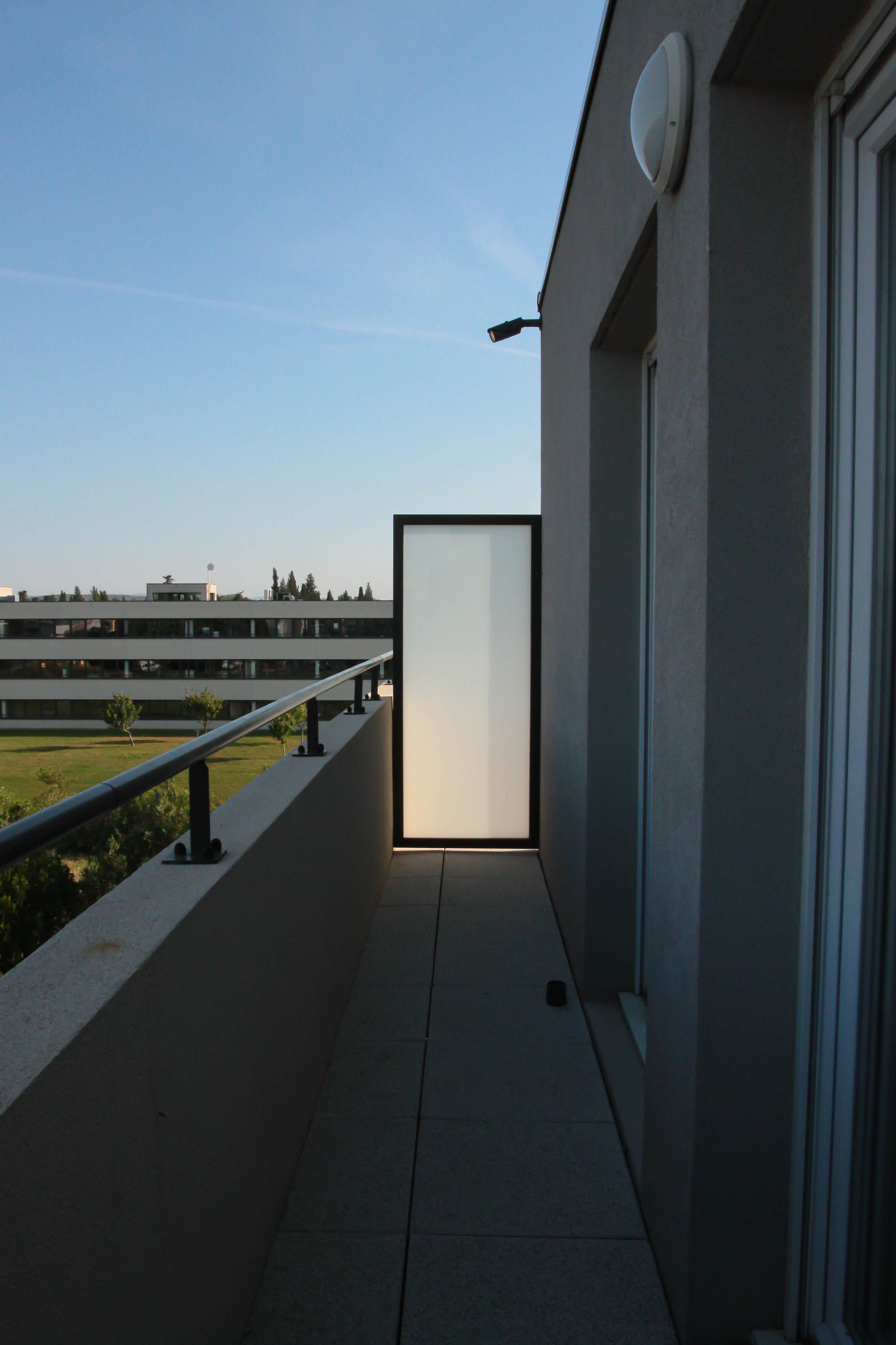 A modern building exterior with a balcony, a door, and a clear sky.