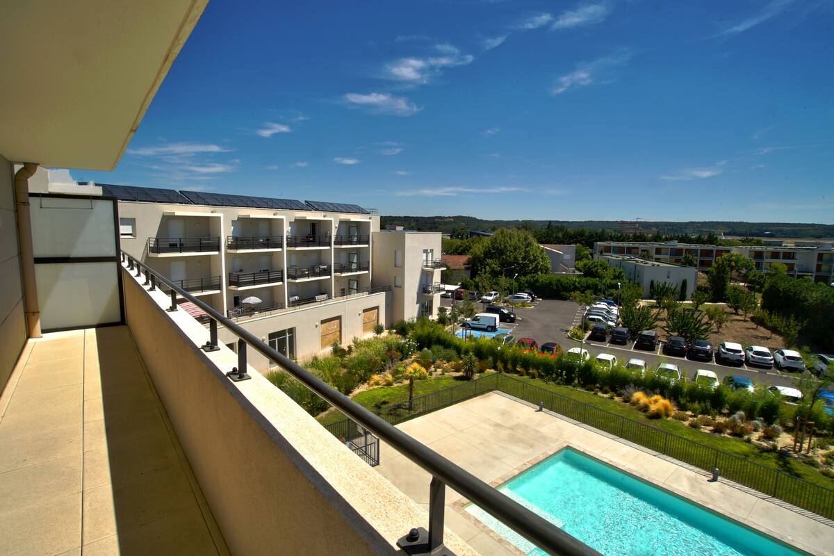 Un hotel con piscina, varios balcones y aparcamiento.