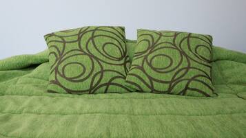 A bed with a green quilt and two pillows with a circular pattern.