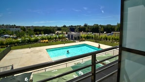 Vista di una piscina sotto un cielo azzurro e circondata da vegetazione.