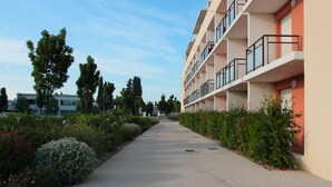 Un edificio moderno con diversi balconi e un vialetto lastricato fiancheggiato da piante.