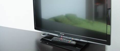 Ein Flachbildfernseher auf einem Ständer mit Fernbedienung, an der Wand befestigt.