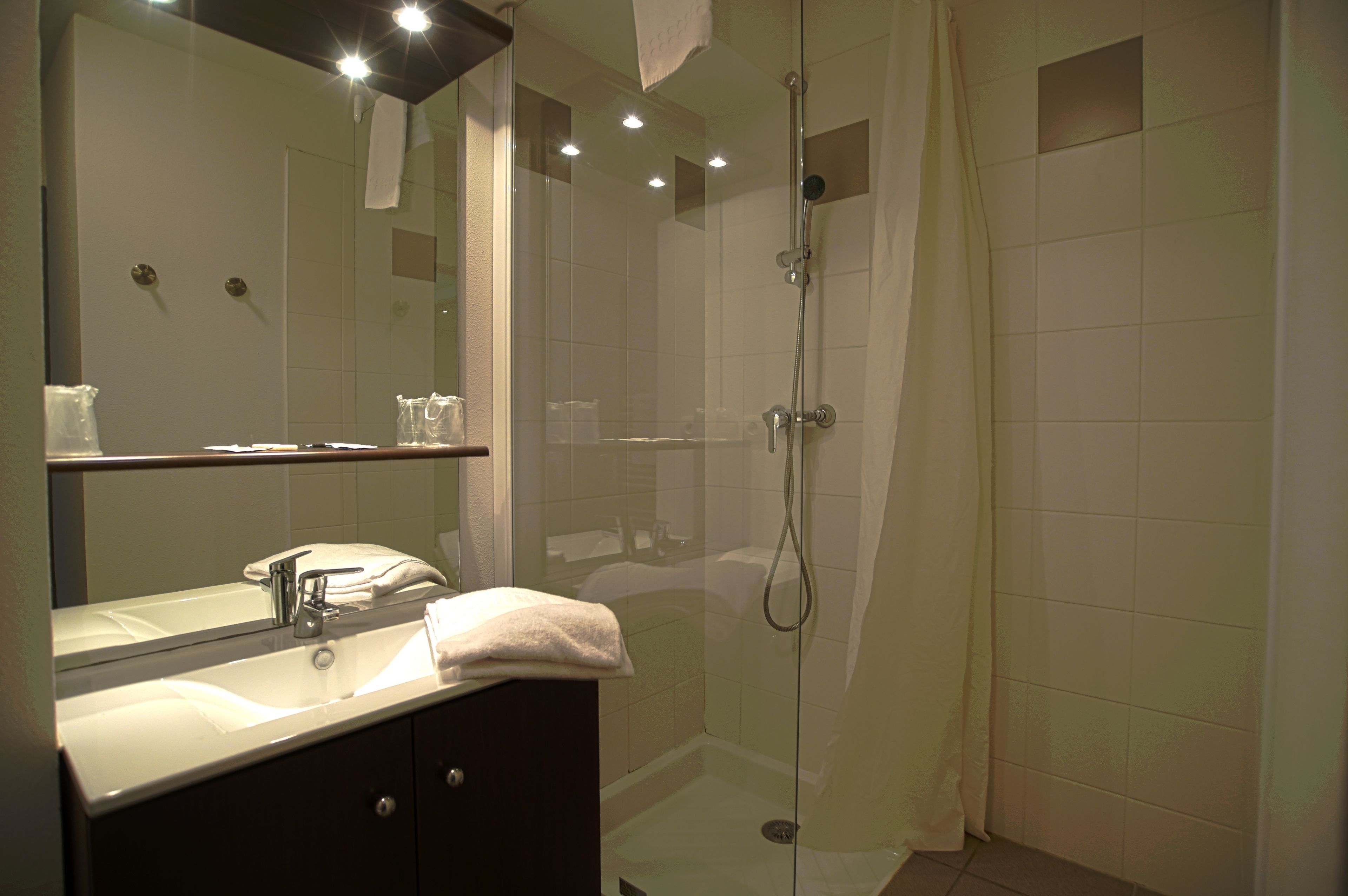 A modern bathroom with a glass-enclosed shower, a vanity with a mirror, and a sink.