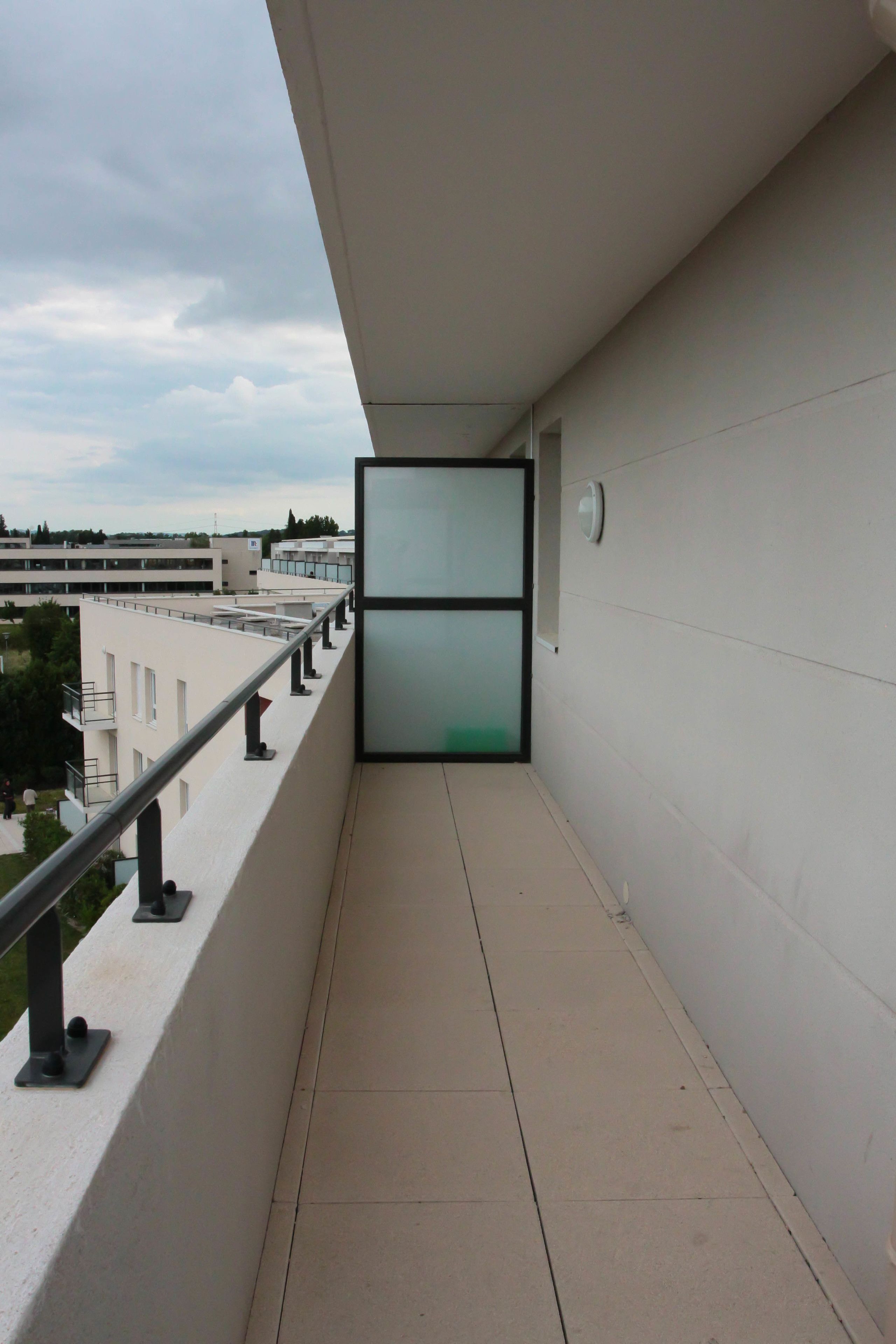 Un couloir étroit avec une porte en verre donnant sur un espace extérieur.