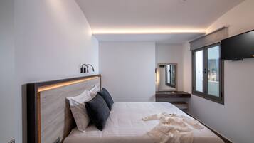 Una habitación de hotel moderna con una cama grande, un televisor de pantalla plana y un ventanal amplio.