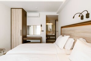A hotel room with a bed, a desk, a mirror, a wardrobe, and a bathroom visible through an open door. - Summer Dream (Rethymno)
