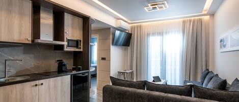 A modern kitchen with built-in appliances, a dining area with a sofa, and a TV mounted on the wall.