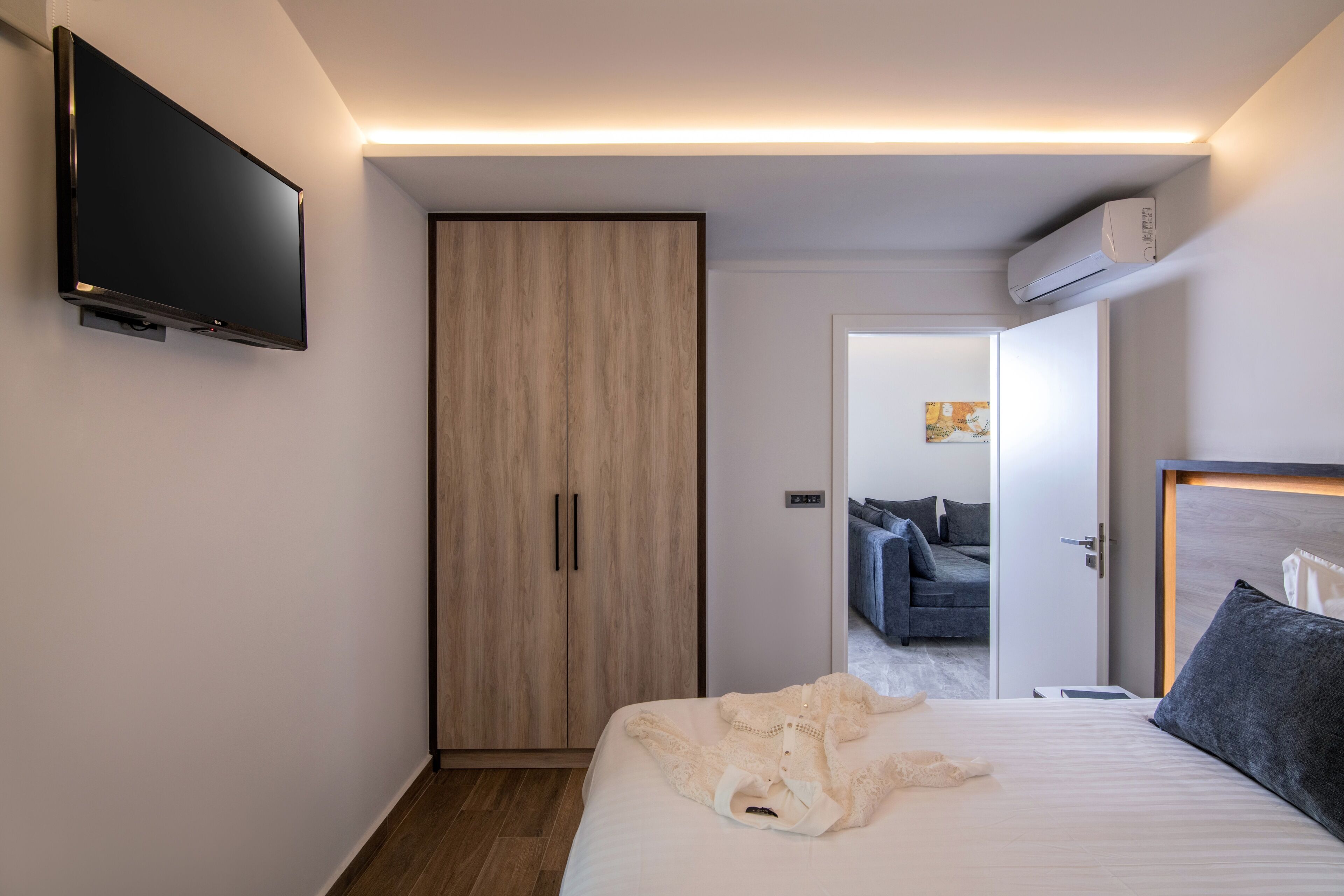 Ein modernes Hotelzimmer mit Bett, Fernseher, Kleiderschrank und Klimaanlage.