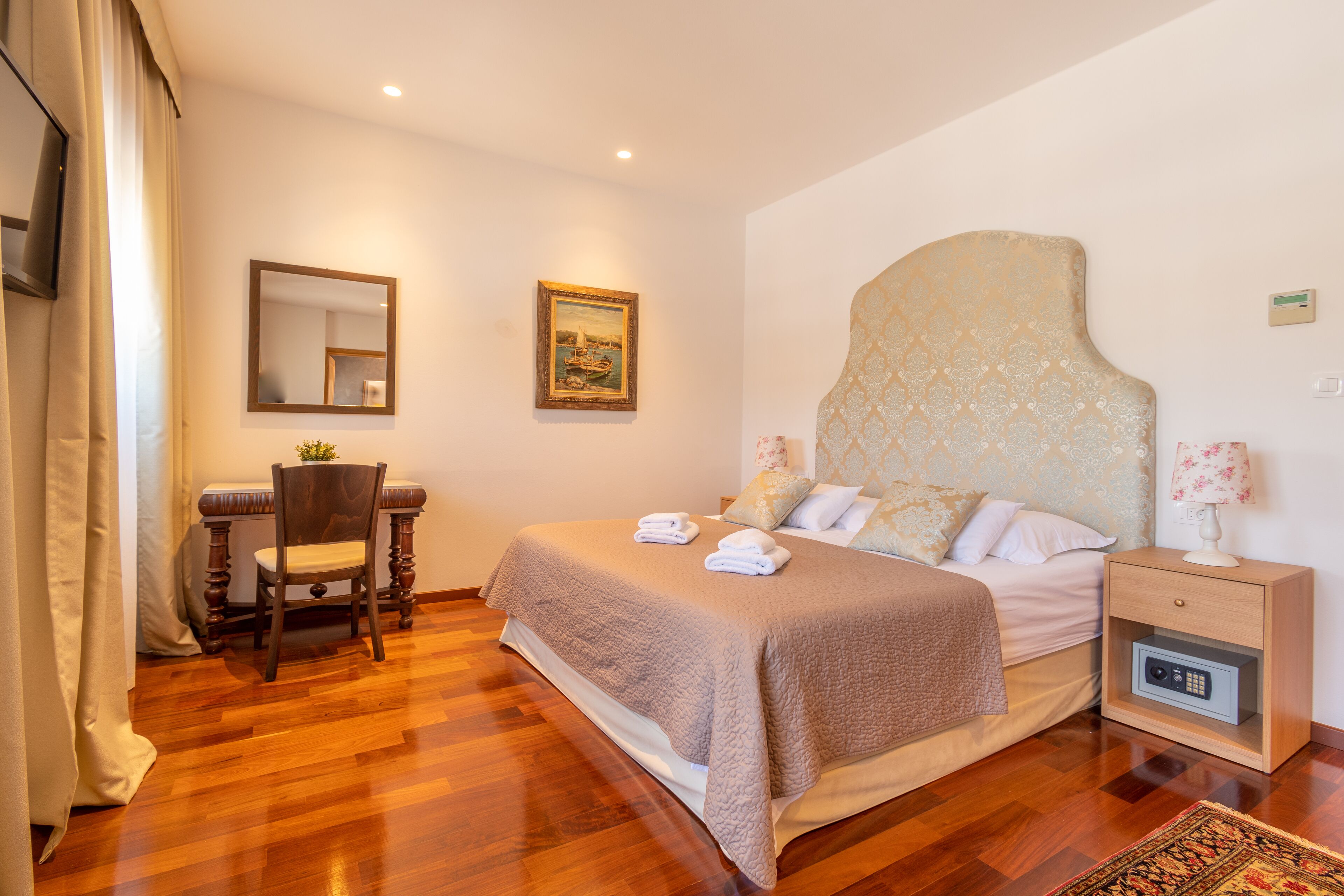 Una habitación de hotel con una cama, una silla, una mesita de noche, una lámpara y un cuadro en la pared.