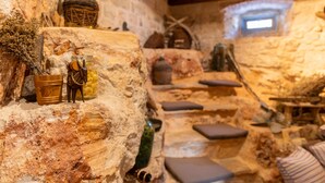 A rustic stone interior with a stone bench, a small table, and a window. - Heritage Villa Apolon (Stari Grad)