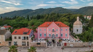 A pink building with a red roof, a stone building with a red roof, and a white building with a dome. - Heritage Villa Apolon (Stari Grad)