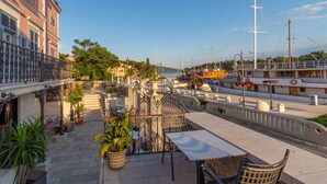A terrace with outdoor seating, a view of the water, and a building with balconies. - Heritage Villa Apolon (Stari Grad)
