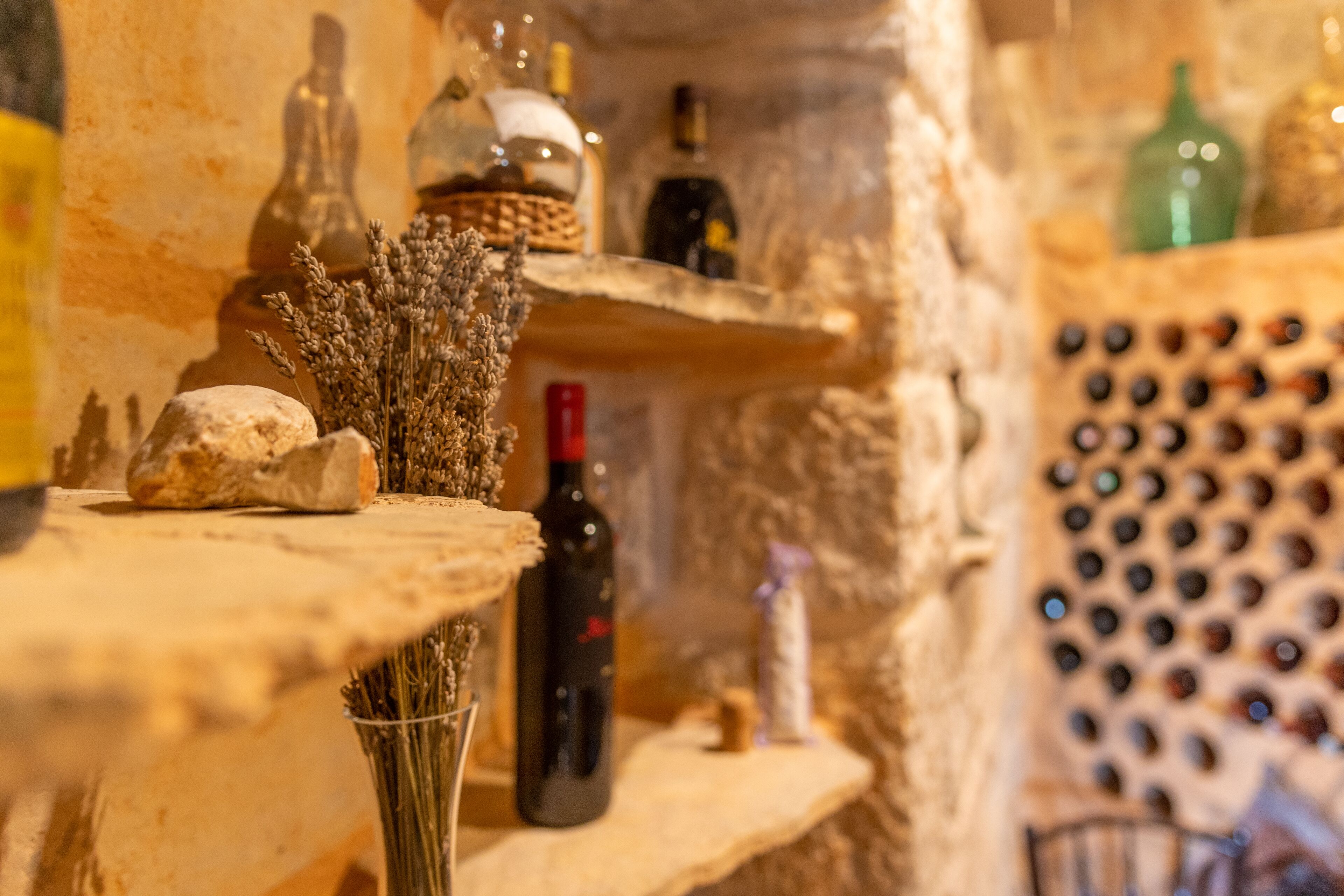 Un interior rústico con paredes de piedra, estanterías con varias botellas y una bodega.