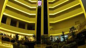 Een moderne hotellobby met een opvallend gewelfd plafond, meerdere verdiepingen en een centrale lift.