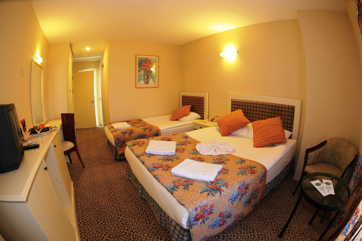 Ein Hotelzimmer mit zwei Betten, einem Schreibtisch mit Fernseher und einem Sessel.